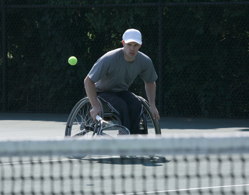 A man in a wheelchair plays tennis