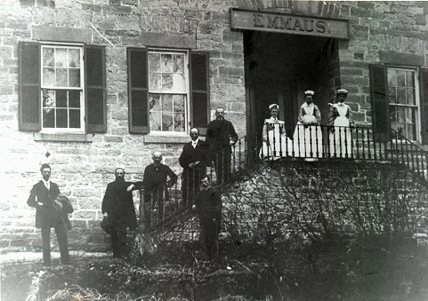 Five doctors and three nurses stand on a staircase in front of a stone building