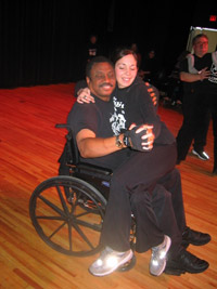 A young woman sits on the lap of a man in a wheelchair.
